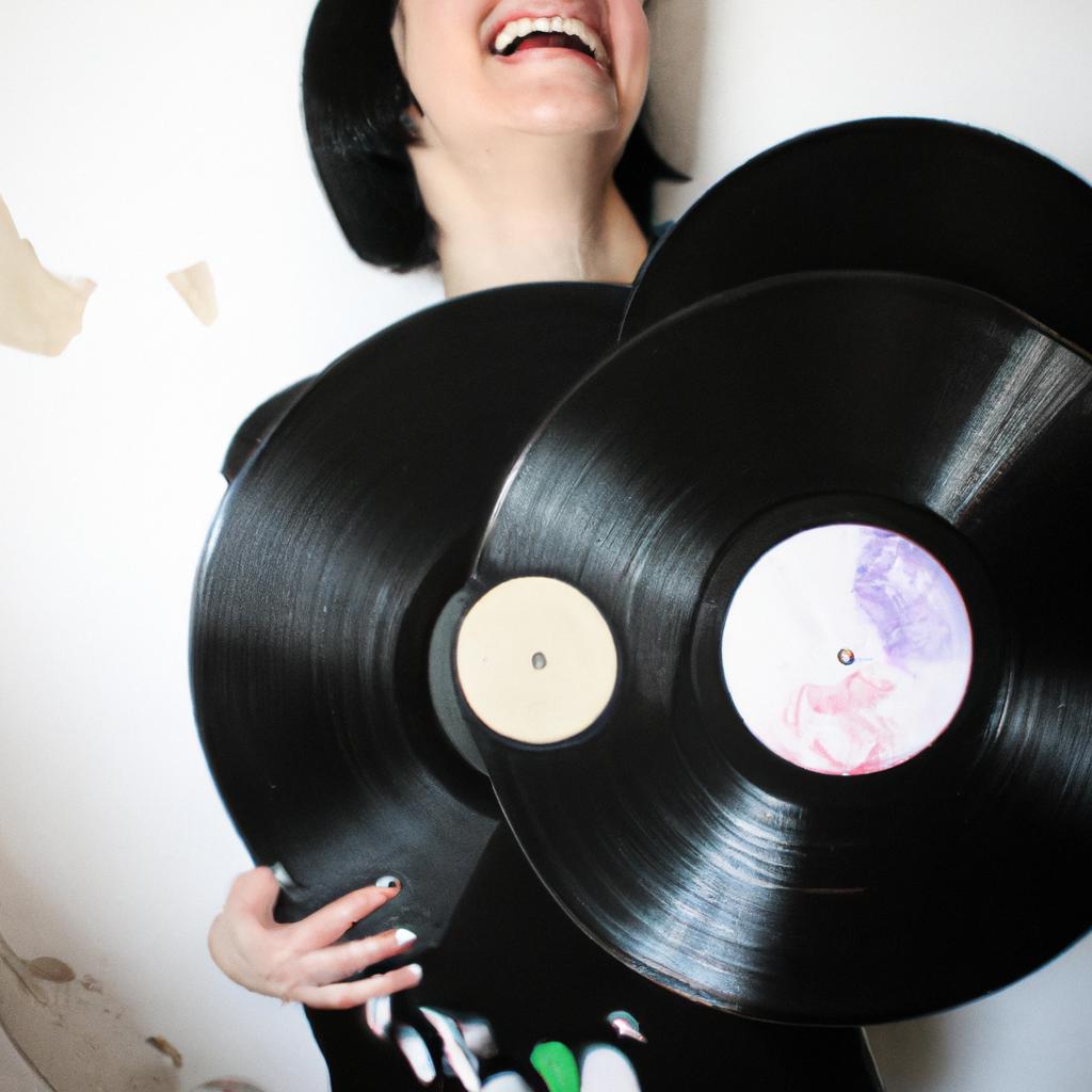 Person holding vinyl records, smiling